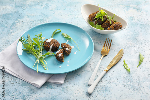 Plate with tasty falafel balls and arugula on color background photo