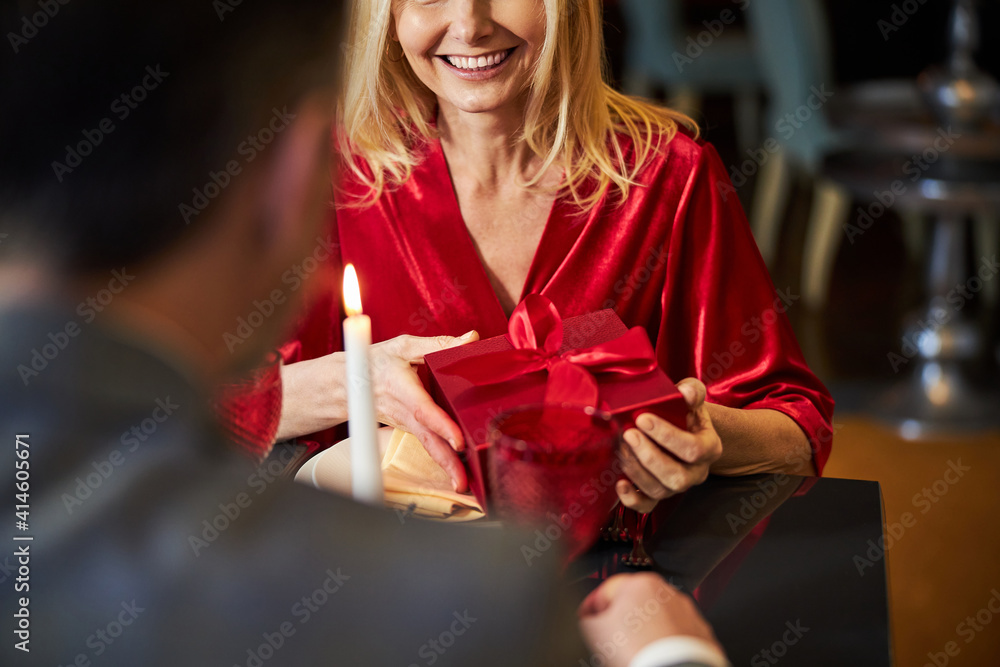 Pleased lady in red dress accepting present from gentleman Pleased lady in red dress accepting present from gentleman