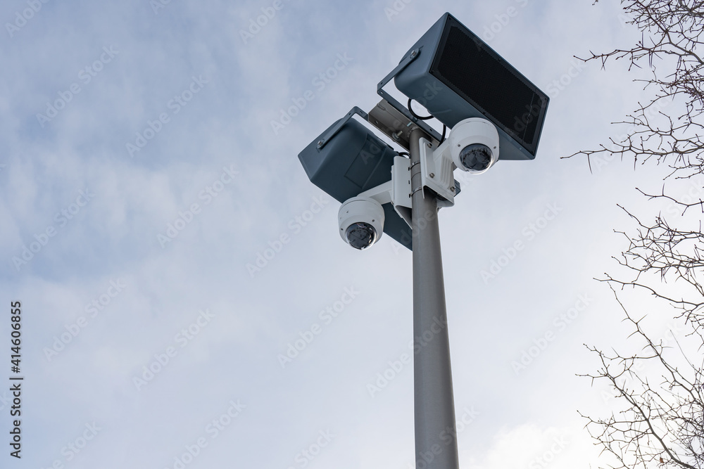 CCTV cameras and loudspeakers on the background of the sky and tree branches with thorns CCTV cameras and loudspeakers on the background of the sky and tree branches with thorns