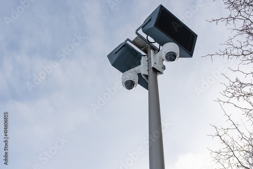CCTV cameras and loudspeakers on the background of the sky and tree branches with thorns