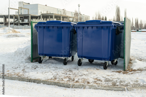 Large blue fenced dumpsters in winter