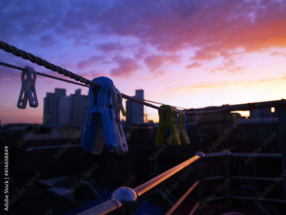 The sunset over the city as you look at the laundry from the rooftop. - obrazy, fototapety, plakaty 