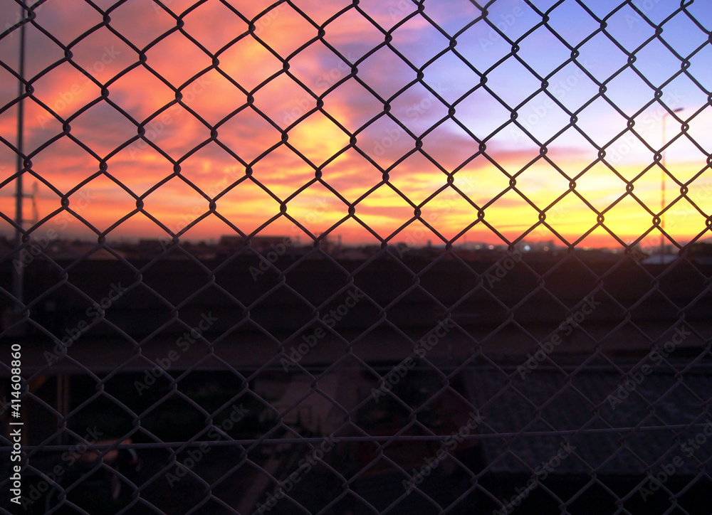 The sunset view of the city through the iron fence. The sunset view of the city through the iron fence.