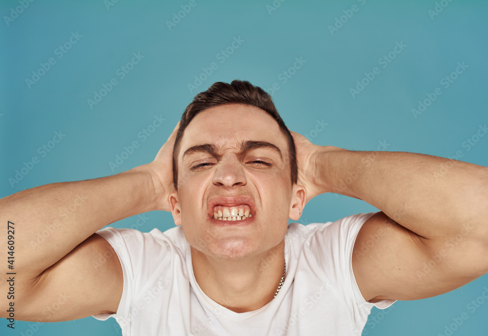 Cute man holds his hand behind his head displeased blue background Cute man holds his hand behind his head displeased blue background