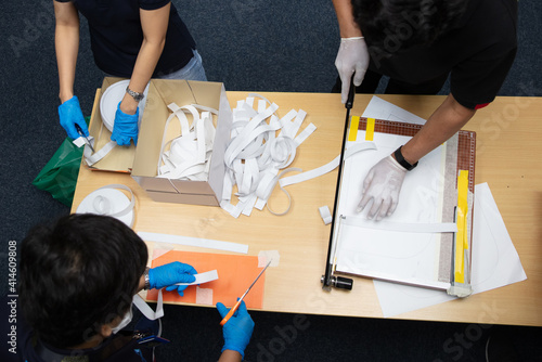 volunteer hand helping to gether to make Face shield to prevent Covid discease, cooperation concpet photo