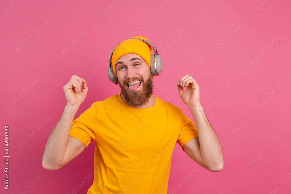 Handsome man in casual dancing with headphones isolated on pink background Handsome man in casual dancing with headphones isolated on pink background