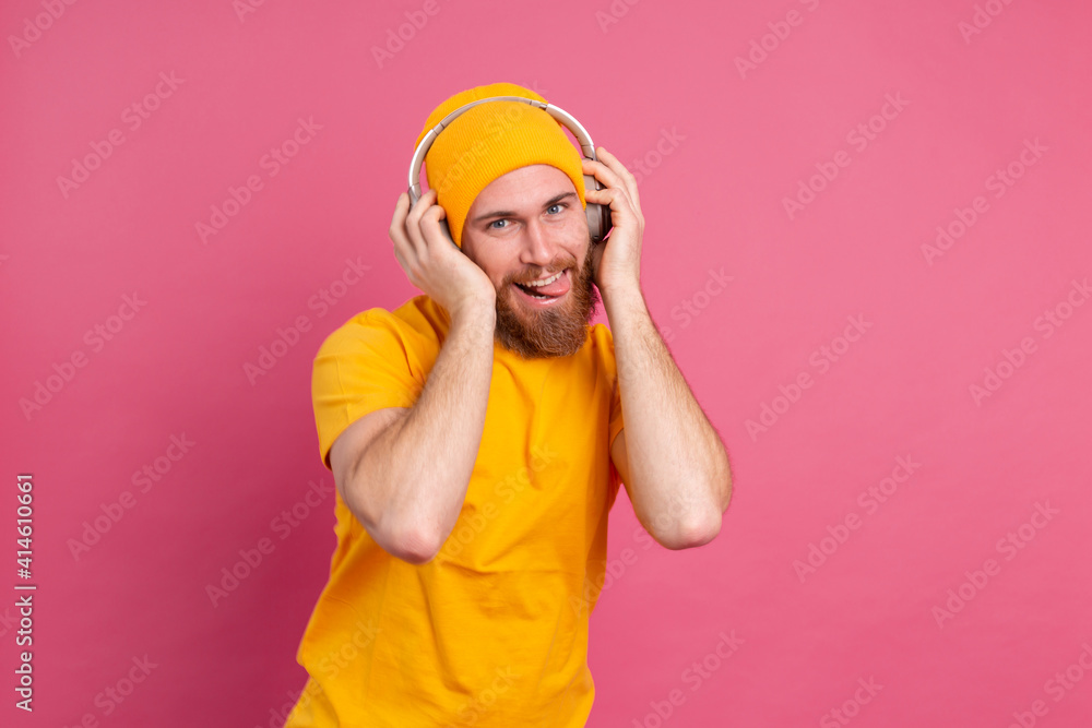 Handsome man in casual dancing with headphones isolated on pink background Handsome man in casual dancing with headphones isolated on pink background