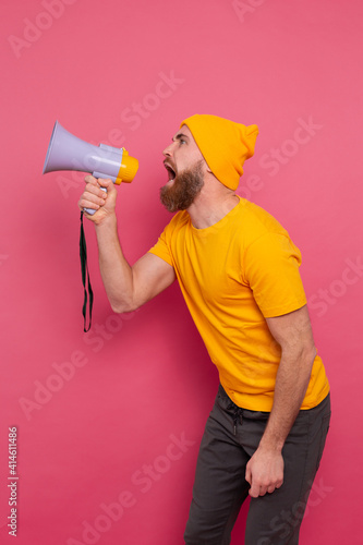Attention! Angry european man shouting in megaphone on pink background