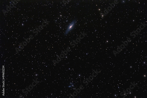 NGC 7331 galaxy and cluster of galaxies photographed with long exposure through a telescope. © astrosystem