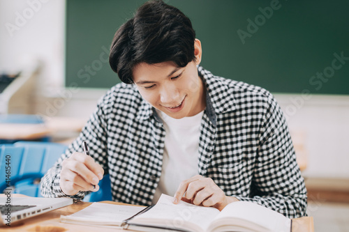 Young cheerful asian student studying in classroom