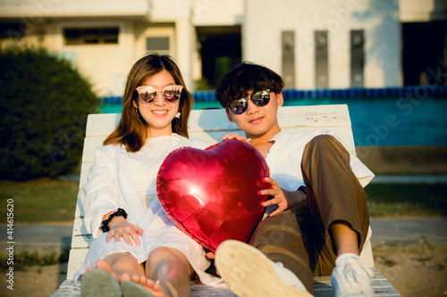 A young couple take vacation at beach side wotj red heard shape balloon photo