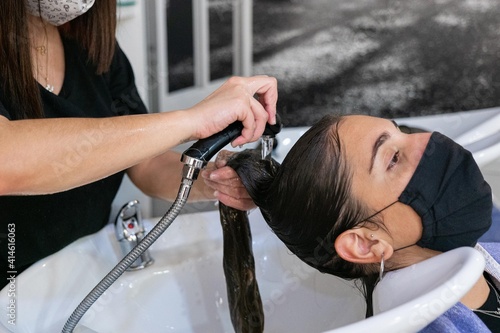 Young hairdresser washing her client's hair