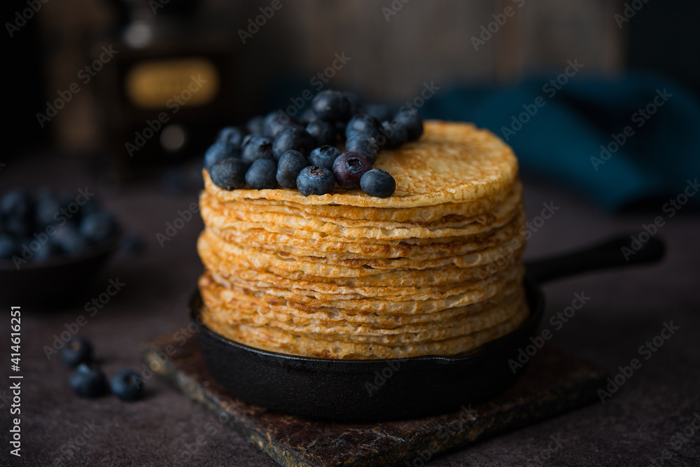 Homemade thin pancakes in a frying pan with blueberries, maslenitsa