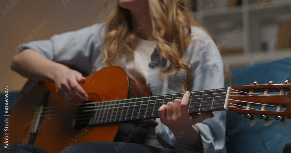 talented woman is playing guitar emotionally and passionately, sitting alone at home at evening, details shot talented woman is playing guitar emotionally and passionately, sitting alone at home at evening, details shot