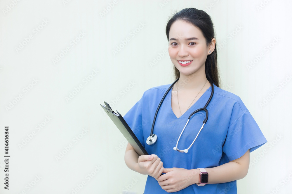Asian beautiful woman doctor standing smiling in a blue lab shirt, holding patient documents in hand. Health care concept Asian beautiful woman doctor standing smiling in a blue lab shirt, holding patient documents in hand. Health care concept