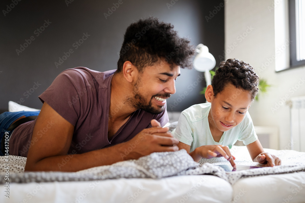 Happy father and son having fun with tablet, smiling at funny video, playing games Happy father and son having fun with tablet, smiling at funny video, playing games