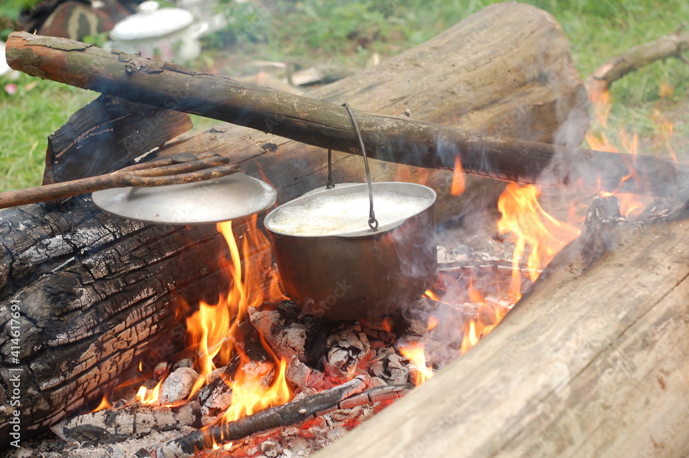 Cooking on an open fire in field conditions. Boiling water in the bowler on the bonfire. Close-up. The camp.  Cooking in the wild.