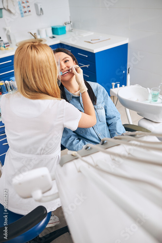 Competent dentist doing teeth cleaning for patient