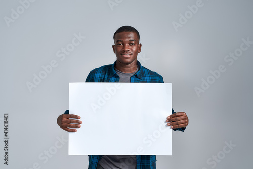 Slika na platnu Cheerful young african american man in casual clothes smiling at camera, display