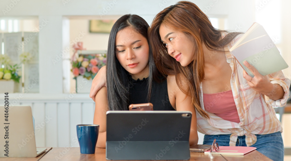 Two young women make fun of each other while reading and using smartphone. Two young women make fun of each other while reading and using smartphone.
