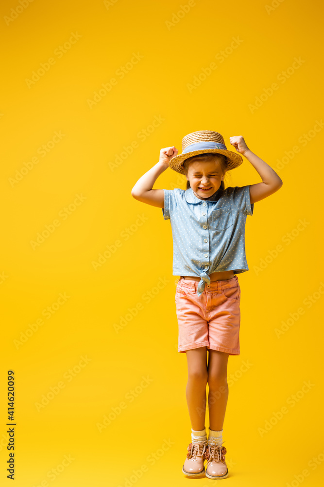 full length of excited kid with clenched fists on yellow full length of excited kid with clenched fists on yellow