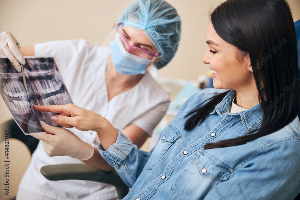 Pretty brunette woman pointing at picture of teeth Pretty brunette woman pointing at picture of teeth