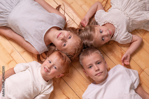 brothers and sisters. 4 children. girls and boys lying on the floor, looking at camera.
