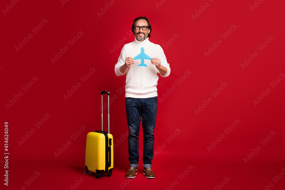 Full body portrait of positive man hands hold paper plane card smile look camera isolated on red color background Full body portrait of positive man hands hold paper plane card smile look camera isolated on red color background