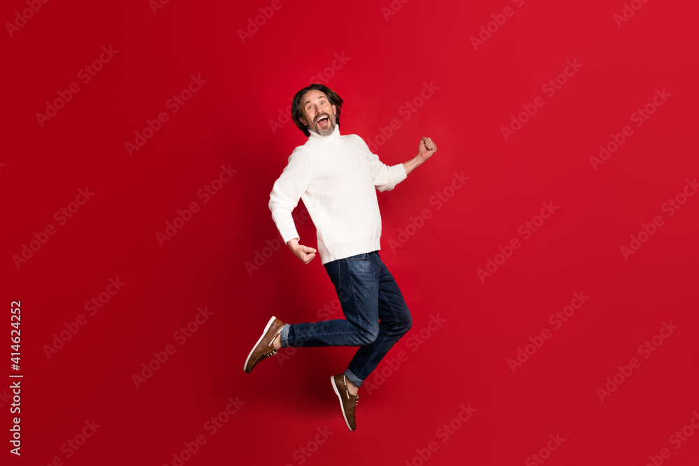 Full size profile portrait of astonished guy jumping open mouth celebrate isolated on red color background Full size profile portrait of astonished guy jumping open mouth celebrate isolated on red color background