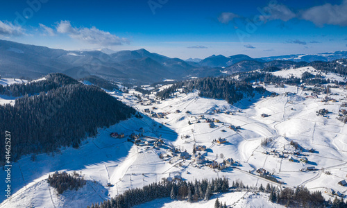 Aerial scenic rural view of the winter landscape from Fundata village in Romania at the bottom of Bucegi Mountains 