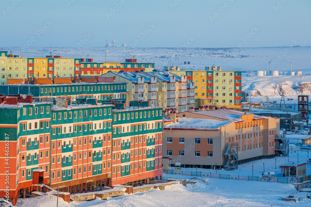 Winter aerial view of a city in the Arctic. View of the colorful residential buildings and the kindergarten building. Snow-covered tundra in the distance. Cold weather. Anadyr, Chukotka, Russia.