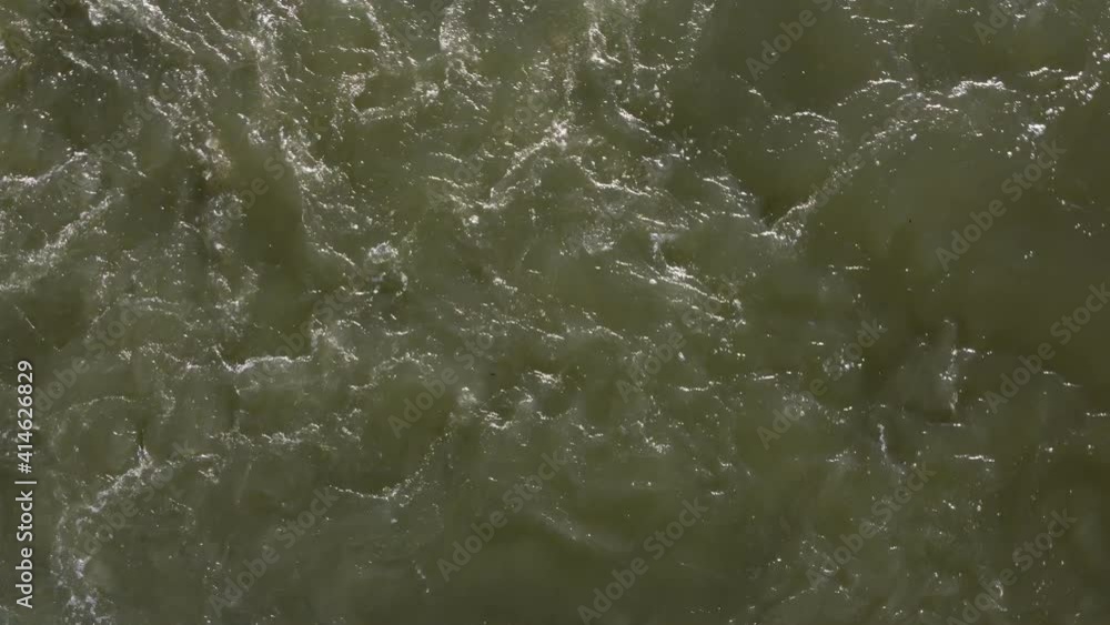 Top view of the turbulent surface of the water. The waves are churning, the river rushing, the place next to the waterfall. Top view of the turbulent surface of the water. The waves are churning, the river rushing, the place next to the waterfall.