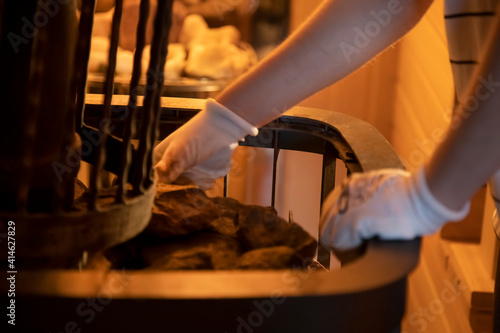 the hands of the master lay stones in the sauna stove