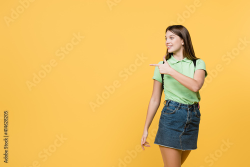 Cheerful teenager pointing with finger isolated on yellow