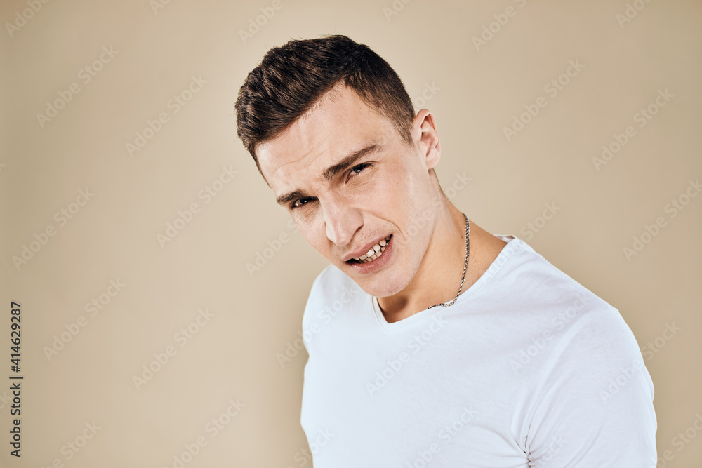 Emotional man white t-shirt gestures with hands lifestyle beige background Emotional man white t-shirt gestures with hands lifestyle beige background