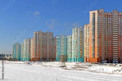 New buildings on snow-covered embankment of Moskva river on background of blue sky. Winter landscape