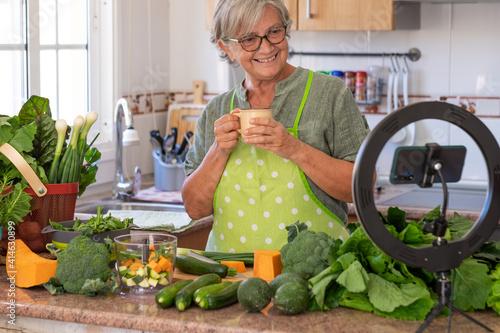 фотографія Smiling senior woman takes a coffee break following online vegetarian cooking lesson