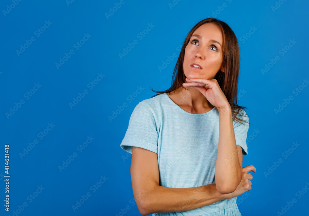 Portrait of a brooding brunette in a blue t-shirt, looking into an empty space, isolated on a blue background. Portrait of a brooding brunette in a blue t-shirt, looking into an empty space, isolated on a blue background.