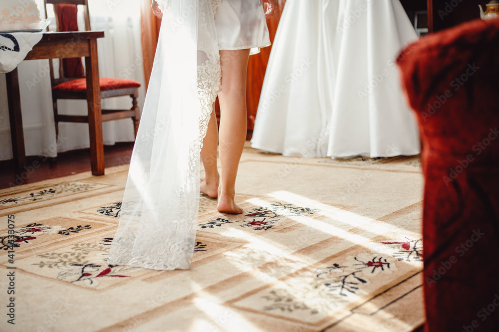 The bride in white dressing gowns and a veil fits into a wedding dress. The  concept of wedding day, bride morning. Bride wearing silk dressing gown  Stock Photo | Adobe Stock