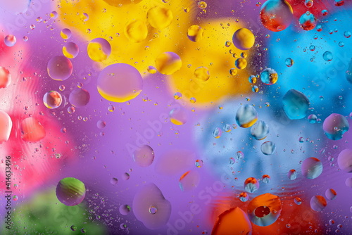 Mixing oil and water drops on a glass. Abstract macro colorful background