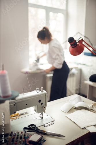 young girl seamstress while working on tailoring in her workshop