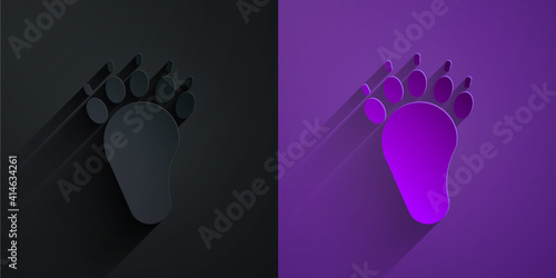 Paper cut Bear paw footprint icon isolated on black on purple background. Paper art style. Vector.