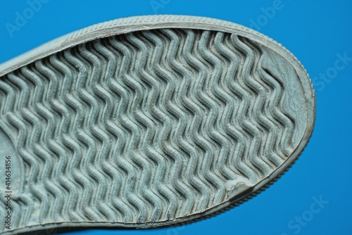 part of a one shoes from a gray white plastic pattern sole on a blue background