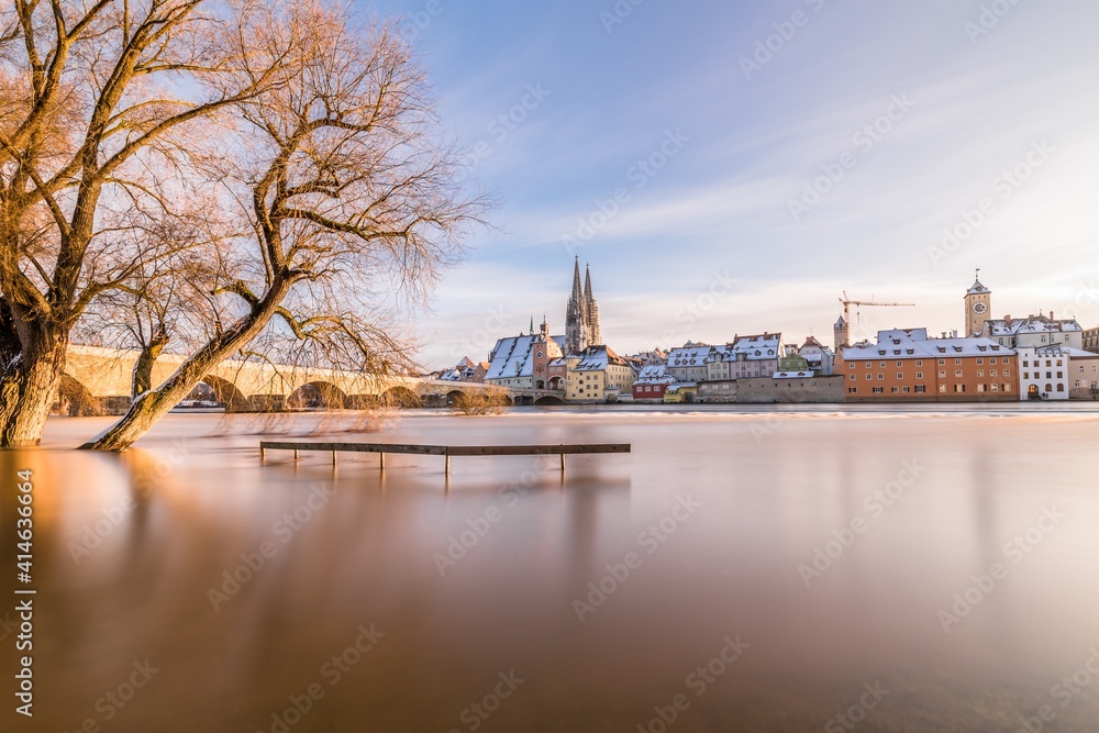 Fototapeta premium Hochwasser des Flusses Donau im Winter 2021 in Regensburg mit Blick auf den Dom die Altstadt und überschwemmte Promenade und der steinerne Brücke, Deutschland
