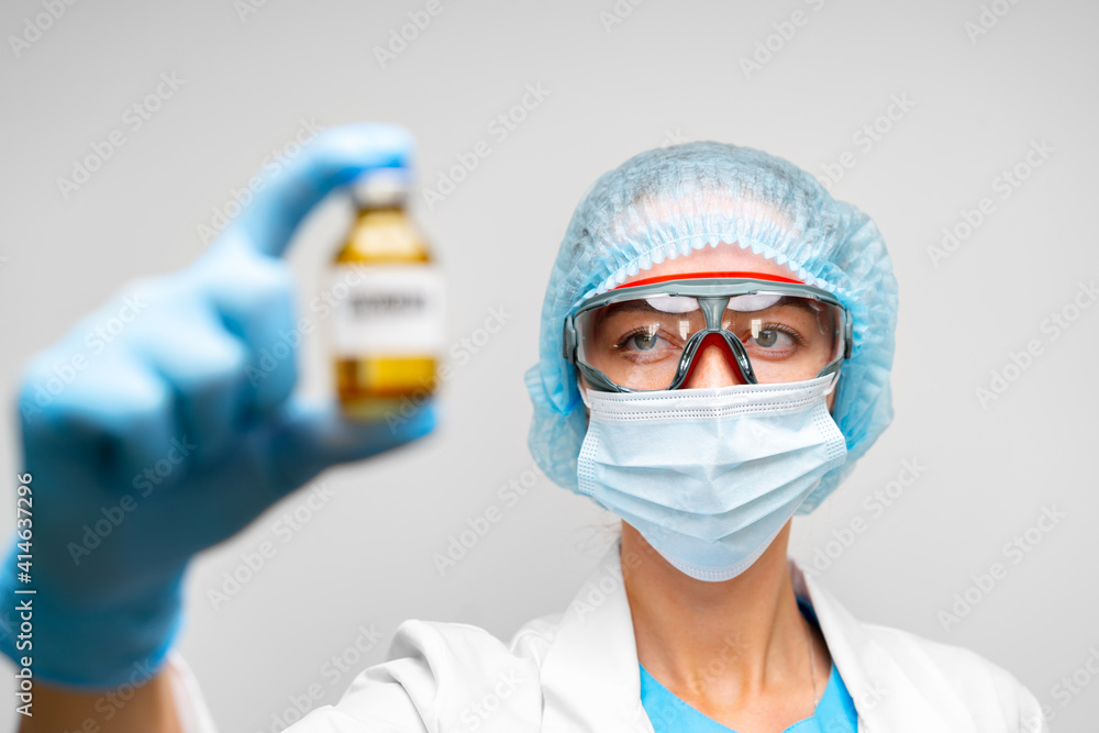 Female doctor in protective suit holding vaccine vial Female doctor in protective suit holding vaccine vial