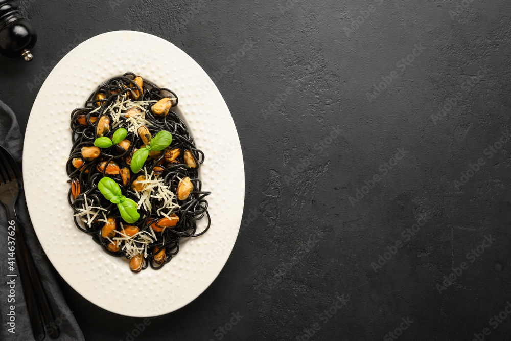 Pasta spaghetti squid Ink with mussels in white plate on black background. View from above. Pasta spaghetti squid Ink with mussels in white plate on black background. View from above.
