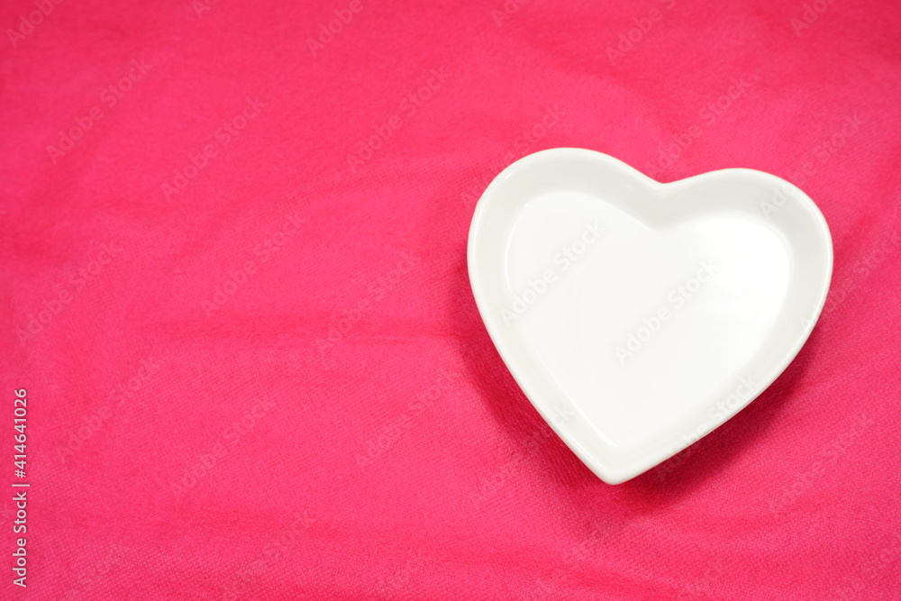 White heart, heart shaped plate-dish, light color heart-shaped plate. Dishes for food, for dinners, weddings or romantic moments. Pink background. Dinner ideas. Sign of romantic.   