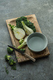 Broccoli and fennel freshly picked and cut on a wooden board. Background has a gray texture