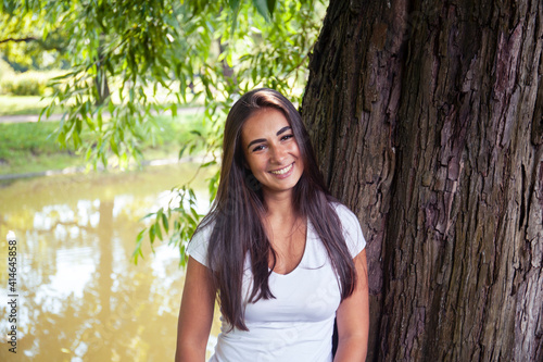 pretty young woman smiling cheerful in green park at tree on summer sunny day, lifestyle people concept