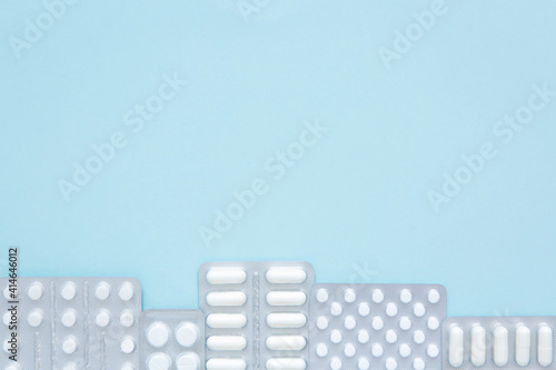 Packs of white pills on blue background  top view. Different medicines  tablets  medicine capsules. Medicine concept  background. Copy space.